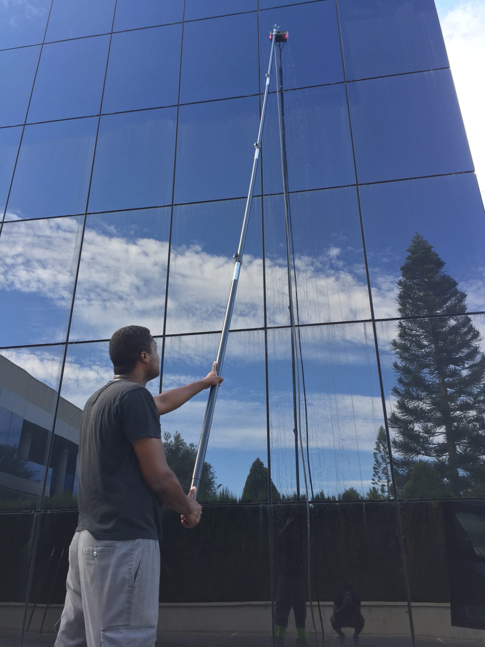 Limpieza de una fachada acristalada con pértiga telescópica.